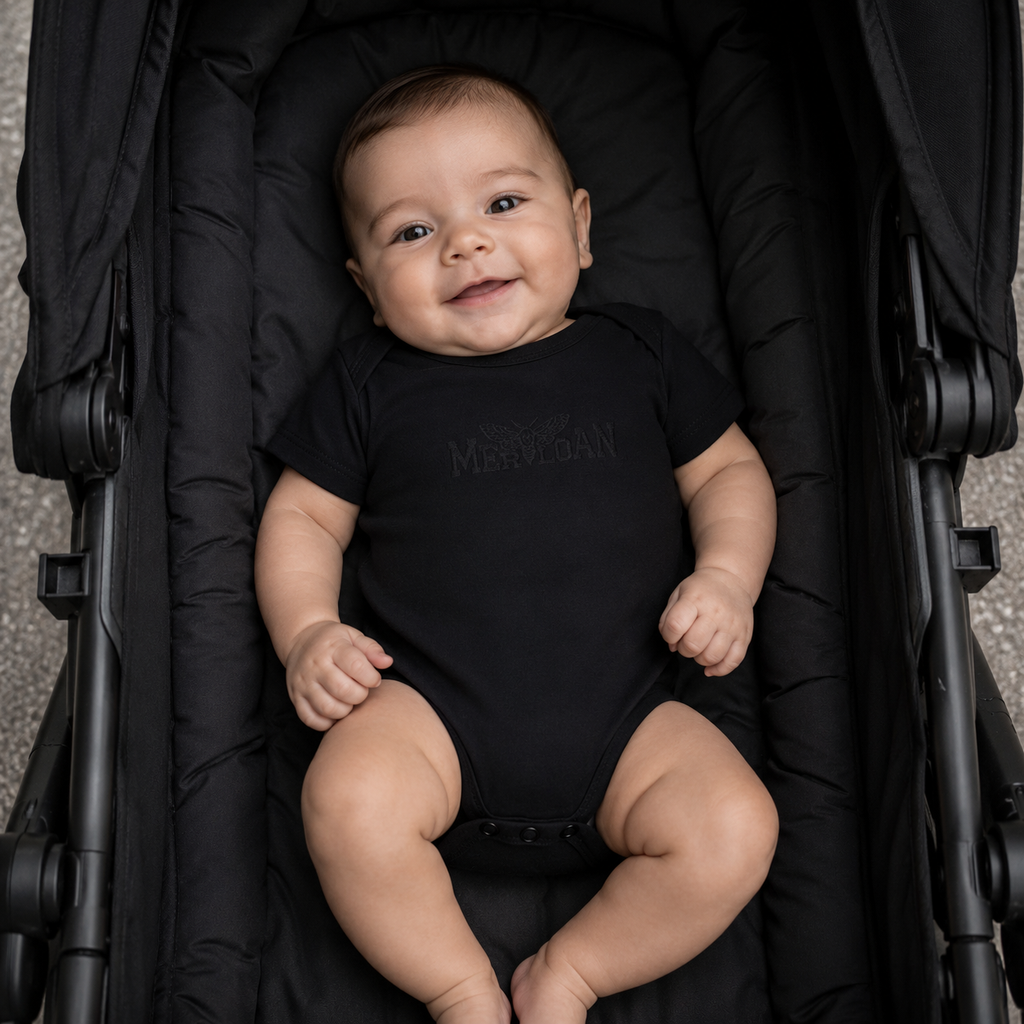 Merloan baby bodysuit, black organic baby bodysuit, organic cotton baby bodysuit, black baby onesie, unisex baby bodysuit, minimalist baby clothing, alternative baby clothes, soft cotton baby bodysuit, stretchy baby bodysuit, envelope neck bodysuit, nickel-free baby bodysuit, sustainable baby clothing, black newborn outfit, Merloan baby basics, organic baby gift